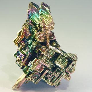 A photograph of a bismuth crystal, showing shimering light refractions and close-up detail.